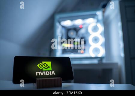 The Nvidia logo is displayed on a smartphone. Nvidia Corporation is a US technology company known for graphics processors. A gaming PC is visible in the background, 18.01.2026. Stock Photo