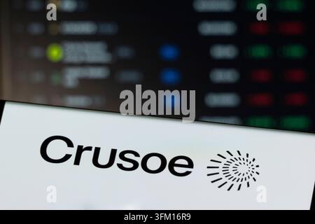 Crusoe logo with a spiral graphic, set against a blurred digital screen background Stock Photo