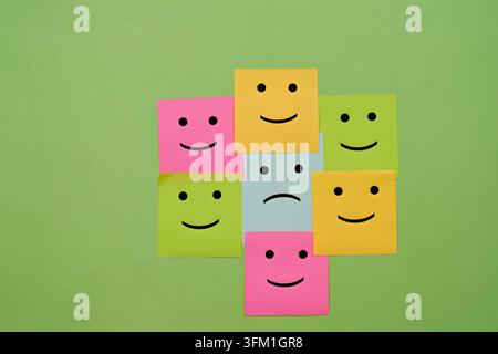 Conceptual image representing various emotions and feedback, featuring colorful sticky notes with smiley and frown faces arranged on a green backgroun Stock Photo