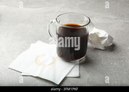 Cup of coffee and stained paper napkin on gray textured table, closeup Stock Photo