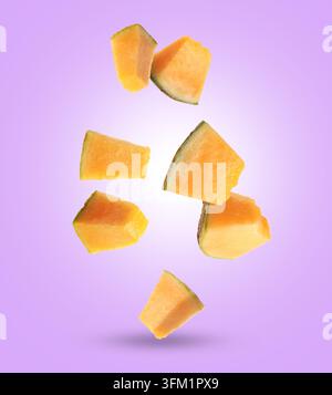 Pieces of cantaloupe melon falling on violet background Stock Photo
