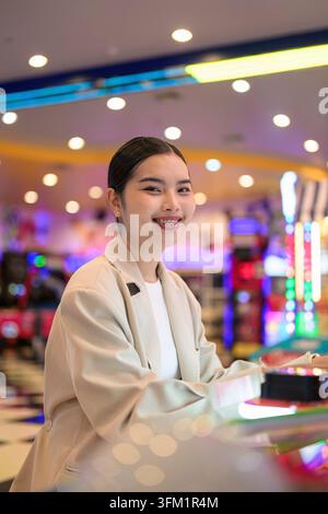 A professional vertical portrait of a cheerful young Southeast Asian Thai businesswoman from the Isan region turning her head to smile directly at the Stock Photo