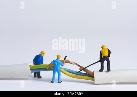 Repair of broken power cable, miniature figure scene, white background, copy space Stock Photo