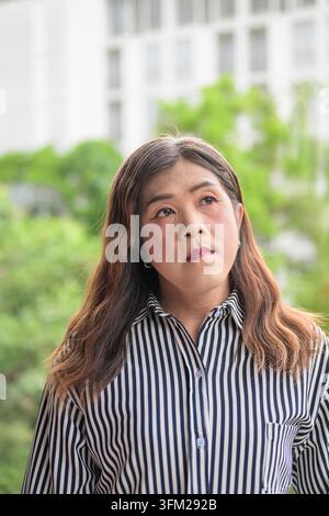 Thai Isan transgender businesswoman vertical portrait outdoors. Vertical close-up portrait of a mature Southeast Asian transgender female wearing a bl Stock Photo
