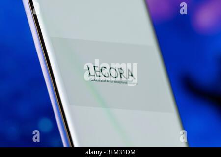 LEGORA logo shown on a smartphone screen, set against a blurred blue background Stock Photo