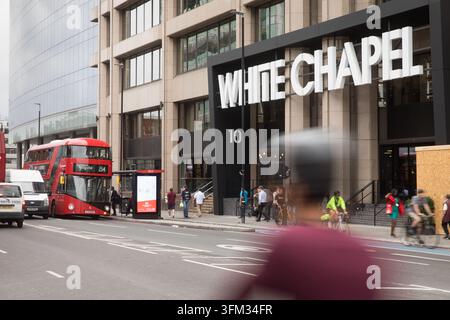 Commuters and cyclists pass the White Chapel Building at 10 Whitechapel High St in Aldgate, London, for daily transit and commuting. Stock Photo