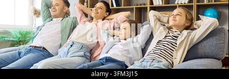Parents and children relaxing on sofa at home, cheerful family together today Stock Photo