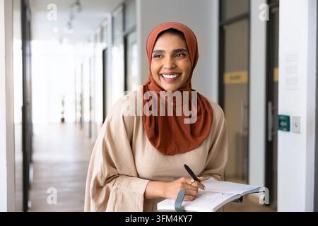 South Asian woman writing in notebook in office Stock Photo