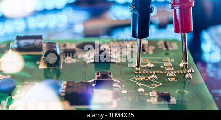 Red and Black Test Probes Inspecting Printed Circuit Board for Electronics Maintenance, Troubleshooting and Quality Control Stock Photo