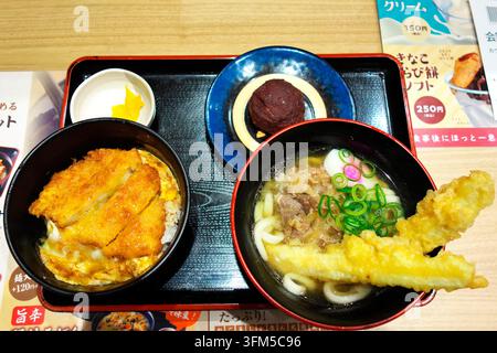 February 08, 2025, Omura, Japan: A traditional Japanese set meal featuring katsudon pork cutlet rice bowl, udon noodles with tempura, side dish, and o Stock Photo