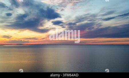 Wispy cirrus clouds and pastel sky over mirror calm sea after sunset Stock Photo