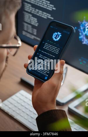 Close up of man using AI chatbot app on his smartphone for business tips, while artificial intelligence assistant or agent on his computer helps him with work and daily tasks on background.  Stock Photo