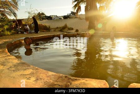 Siwa, Egypt - November 28 2012: People relax in spring water at an oasis in Siwa. Stock Photo
