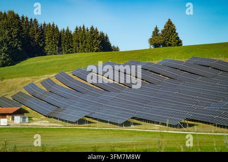 Deutschland, Allgäu: Große Freiflächen-Photovoltaikanlage mit zahlreichen Solarmodulen auf einer grünen Wiesenfläche in ländlicher Landschaft. Photovoltaik, Solaranlage, Solarpark, Solarmodule, Solarenergie, Sonnenenergie, erneuerbare Energien, Energiewende, Stromerzeugung, Energieversorgung, Ökostrom, Klimaschutz, Nachhaltigkeit, Energiepolitik, Infrastruktur, Landwirtschaft, Flächennutzung, Allgäu, Bayern, Deutschland, Symbolfoto. *** Germany, Allgäu: Large-scale ground-mounted photovoltaic system with numerous solar modules on a green meadow in a rural landscape photovoltaics, solar system, Stock Photo