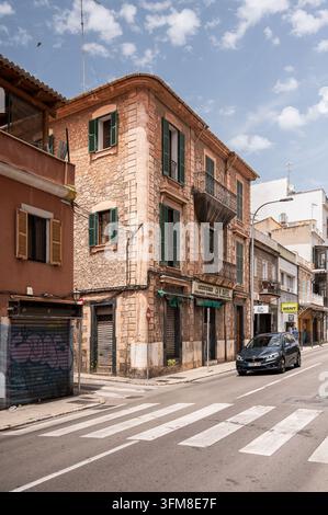 Historic stone corner building with green shutters and balconies in an urban street in Palma de Mallorca Stock Photo