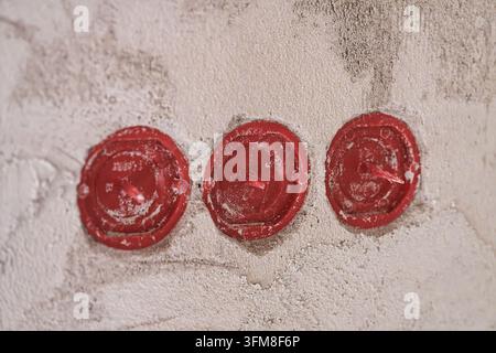 Three red plaster covers on electrical installation boxes embedded in a rough plastered wall showing construction details during interior renovation w Stock Photo