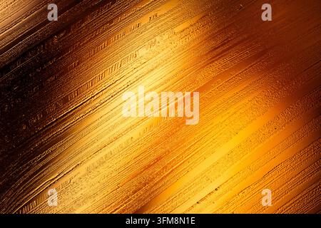 Golden metallic background showing abstract texture with diagonal lines and glowing light, creating a luxurious and elegant surface Stock Photo
