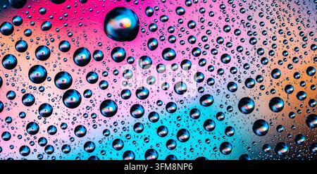Water drops creating a bright and colorful abstract background with gradients of pink, blue, and orange, showing natural moisture Stock Photo