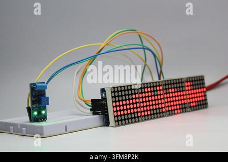 Red dot matrix display module and vibration sensor connected on a breadboard displaying various patterns Stock Photo