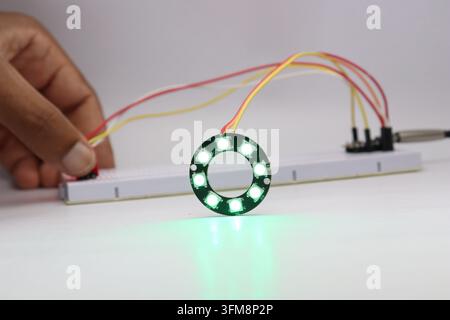 ARGB LED ring light glowing in color controlled by a sensor and microcontroller in the background Stock Photo