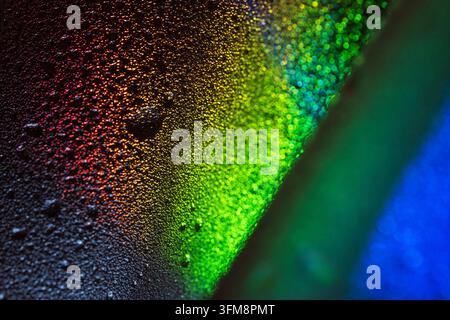 Water droplets forming on a textured surface, creating a vibrant abstract background with colorful light refractions and bokeh Stock Photo