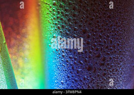Water droplets cover a textured film surface, creating a vibrant abstract pattern with colorful light reflections and bokeh Stock Photo