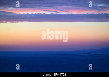 Soft pastel sunset over calm ocean with layered cloud bands and wide horizontal gradient, minimalist seascape for backgrounds and travel visuals Stock Photo