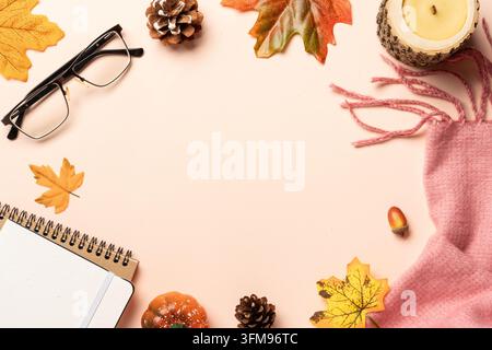 Autumn flat lay background. Autumn leaves, notepad, scarf, candle and spices on yellow background. Stock Photo