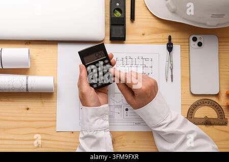 Construction budget and project planning, architect using calculator for building cost estimation with blueprints and engineering tools on wooden desk Stock Photo