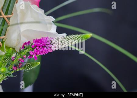 Floral arrangement featuring white rose and pink flowers, green foliage, balanced composition, soft elegant appearance, vibrant colors, natural backdr Stock Photo