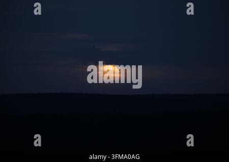 The sun setting behind dark clouds and a distant horizon. Stock Photo