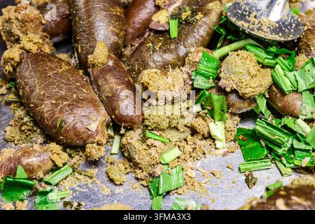 Steamed snakehead fish roe coated in seasoning with chopped culantro and chili, on a metal surface with a stainless steel scoop. Stock Photo