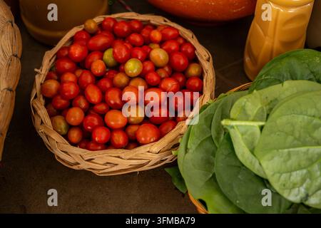 Colorful cherry tomatoes and vibrant green leaves. Likely spinach or similar greens. Neatly arranged in natural woven baskets. Showcasing fresh. Organ Stock Photo