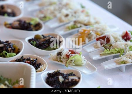 Small white bowls and spoons filled with various rice dishes and vegetables Stock Photo