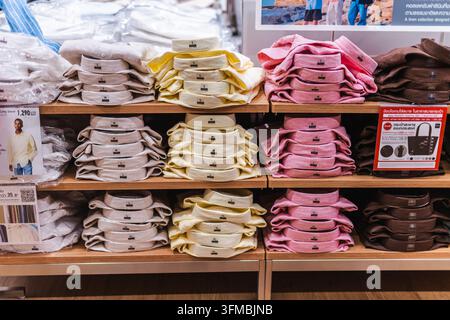 Bangkok, Thailand, May 4, 2026: Colorful folded shirts in pink, yellow, beige, and brown are arranged by size on retail shelves. Stock Photo