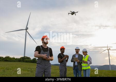 Diverse team of engineers using drone technology for wind turbine inspection Stock Photo