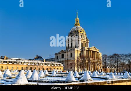 The gilded dome of Hotel des Invalides and snow covered topiary garden under a clear blue sky in winter in Paris, France. Stock Photo