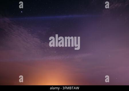 Beautiful pink and purple gradient twilight sky with wispy cirrus clouds and stars emerging, perfect for sunset and evening atmosphere backgrounds. Stock Photo