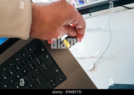 Laptop memory card slot inserting SD card data storage offload footage. A high capacity digital storage card is inserted into a modern computer reader Stock Photo