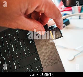 Inserting high speed SD memory card laptop slot data transfer offload backup. A close-up shot of a photographer or videographer inserting a high-perfo Stock Photo
