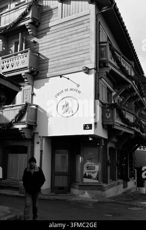 Man walks past the heart-carved balconies of the Cœur de Megève building in b&w Stock Photo