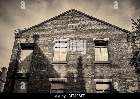 Old Victorian factory in the shadow of church building,UK Stock Photo