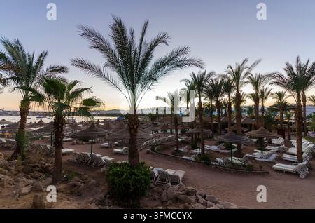 People relax and enjoy the beach at sunset. Stock Photo