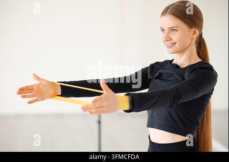 Smiling woman doing arm exercises with a resistance band Stock Photo