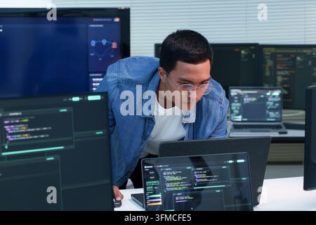 Programmer working with software code on multiple screens, representing digital development, artificial intelligence, cybersecurity, and modern techno Stock Photo