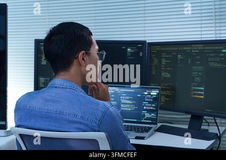 Programmer Developing Software with Multiple Code Screens Stock Photo