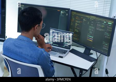 Programmer Developing Software with Code on Multiple Screens Stock Photo
