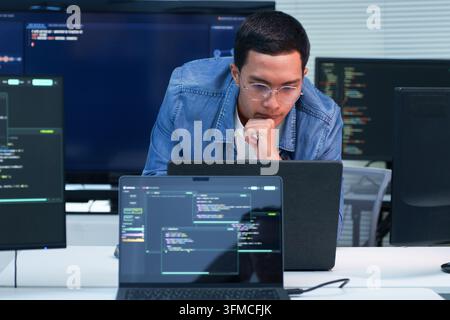 Focused programmer working on software development, digital technology, artificial intelligence, and cybersecurity code using a laptop. Stock Photo