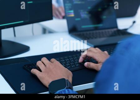 Developer typing code on a laptop, focused on software programming, digital technology, artificial intelligence, and cyberspace development. Stock Photo