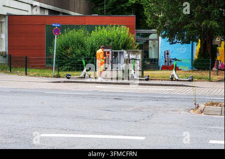 Hagen, Germany - July 22, 2026: A technician in high-visibility clothing repairs an open electrical street distribution cabinet on a sidewalk. Stock Photo